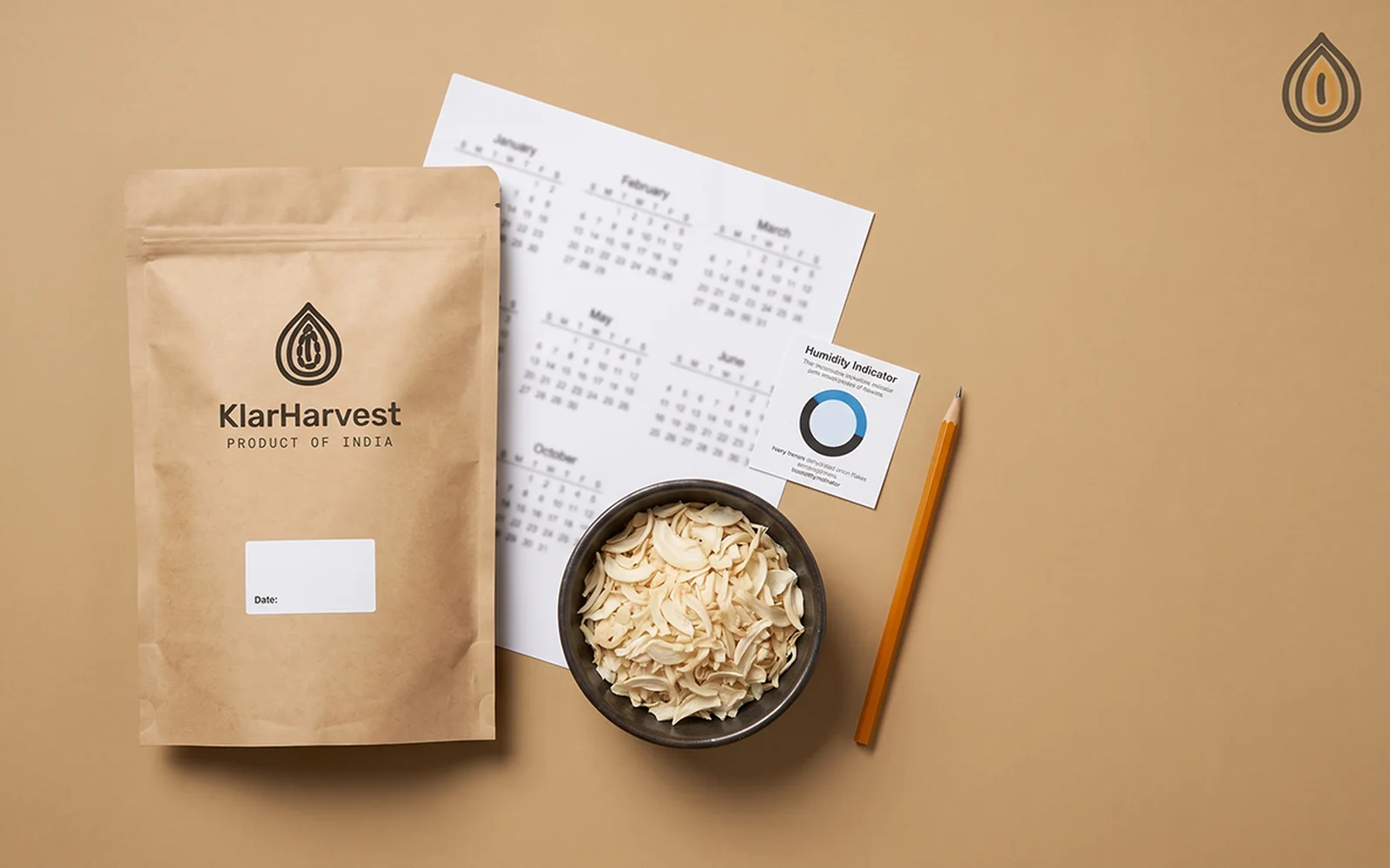 Sealed kraft sack with a date label, a calendar page, a humidity card and a bowl of onion flakes on a plain backdrop