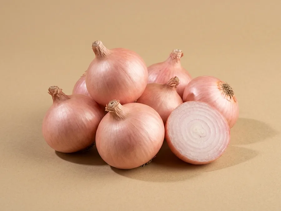 Whole fresh pink onions with light pink papery skins, one halved to show pale rose rings.