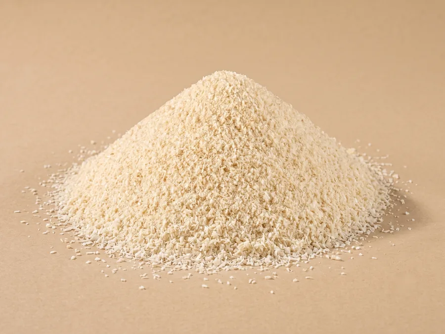 Dehydrated white onion granules, 0.5 to 1 mm, free-flowing cream grains formed into a cone on kraft paper.