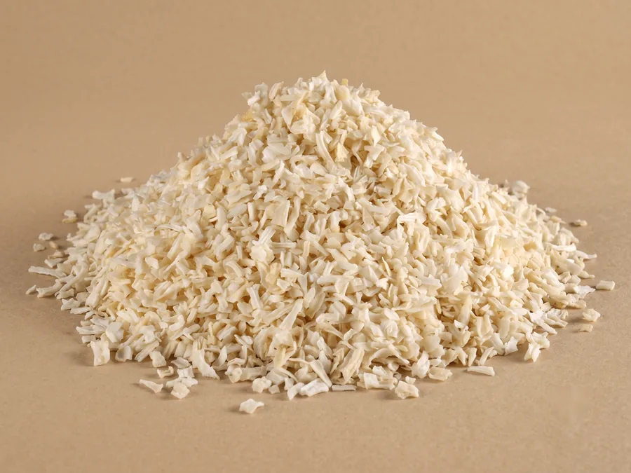 Dehydrated white onion, minced grade, a fine 1 to 3 mm cream crumb heaped on kraft paper.
