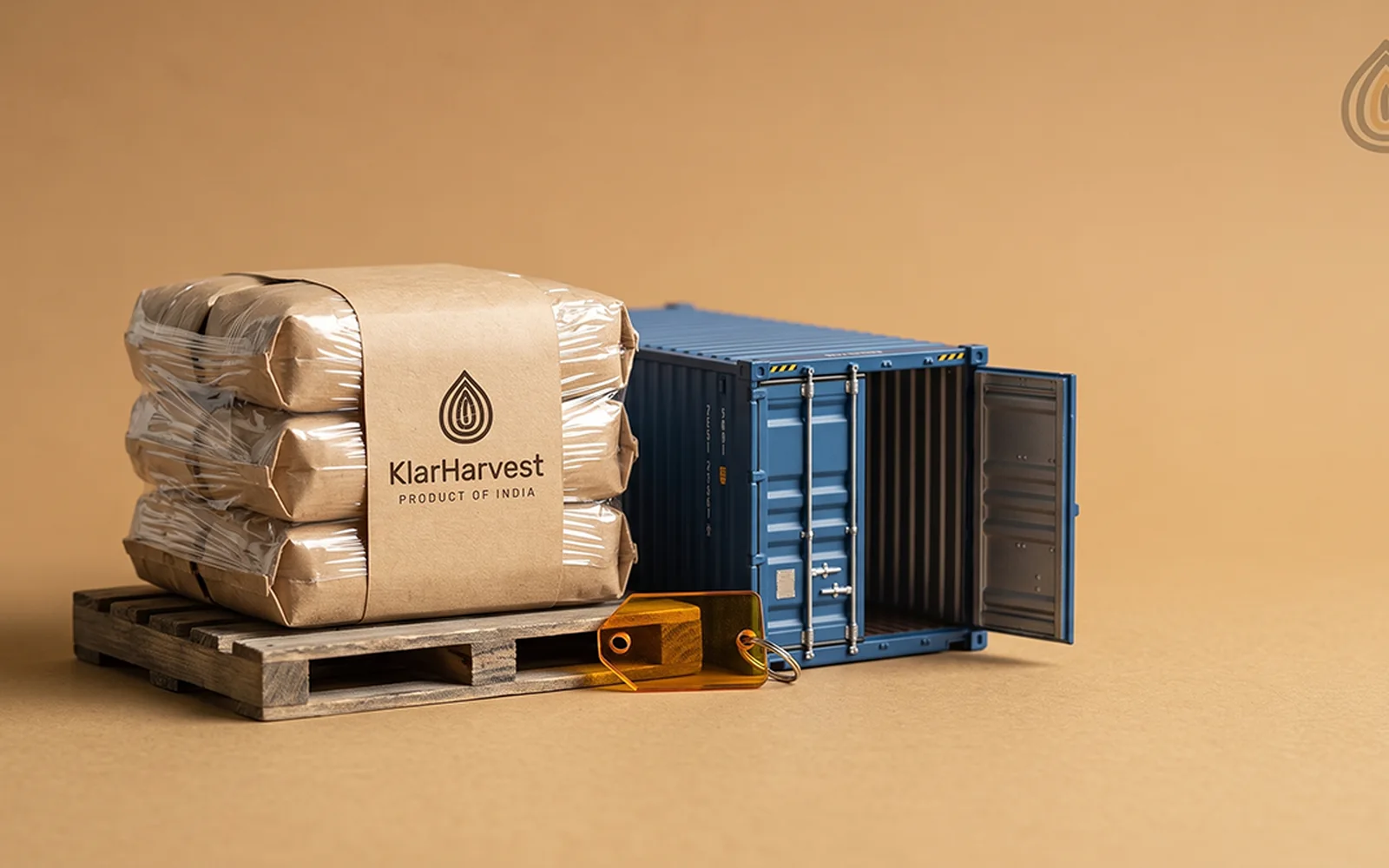 Three wrapped kraft sacks on a small pallet beside a model shipping container with open doors on a plain backdrop