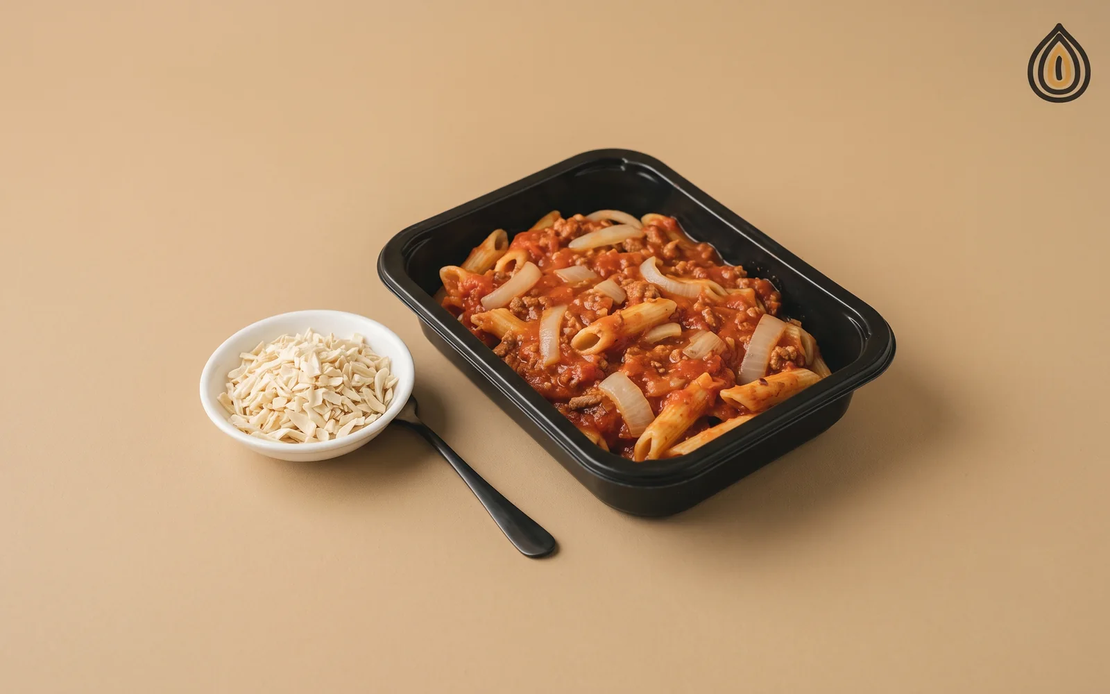 Chilled pasta ready-meal tray with visible onion pieces in the sauce beside a dish of dried chopped onion on a steel bench