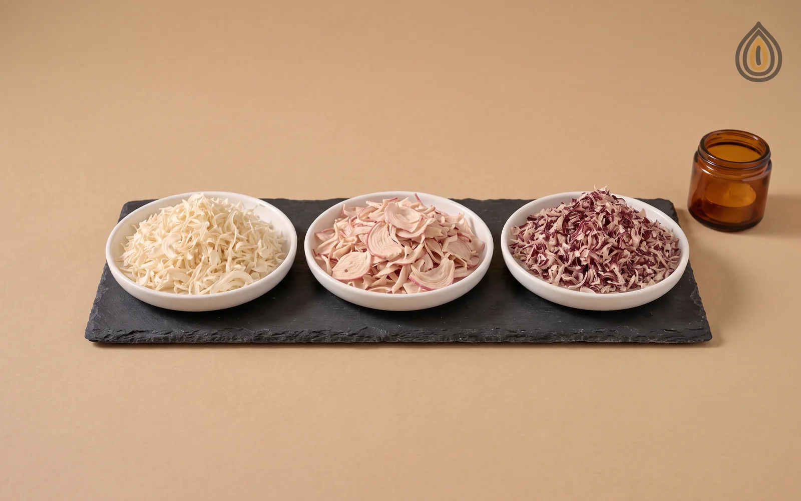Three dishes of dehydrated onion flakes on slate, white, pink and red side by side, the pink visibly between the two